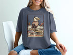 T-shirt graphic of an eagle surfing with text "UNBOTHERED COASTAL AMERICANA".