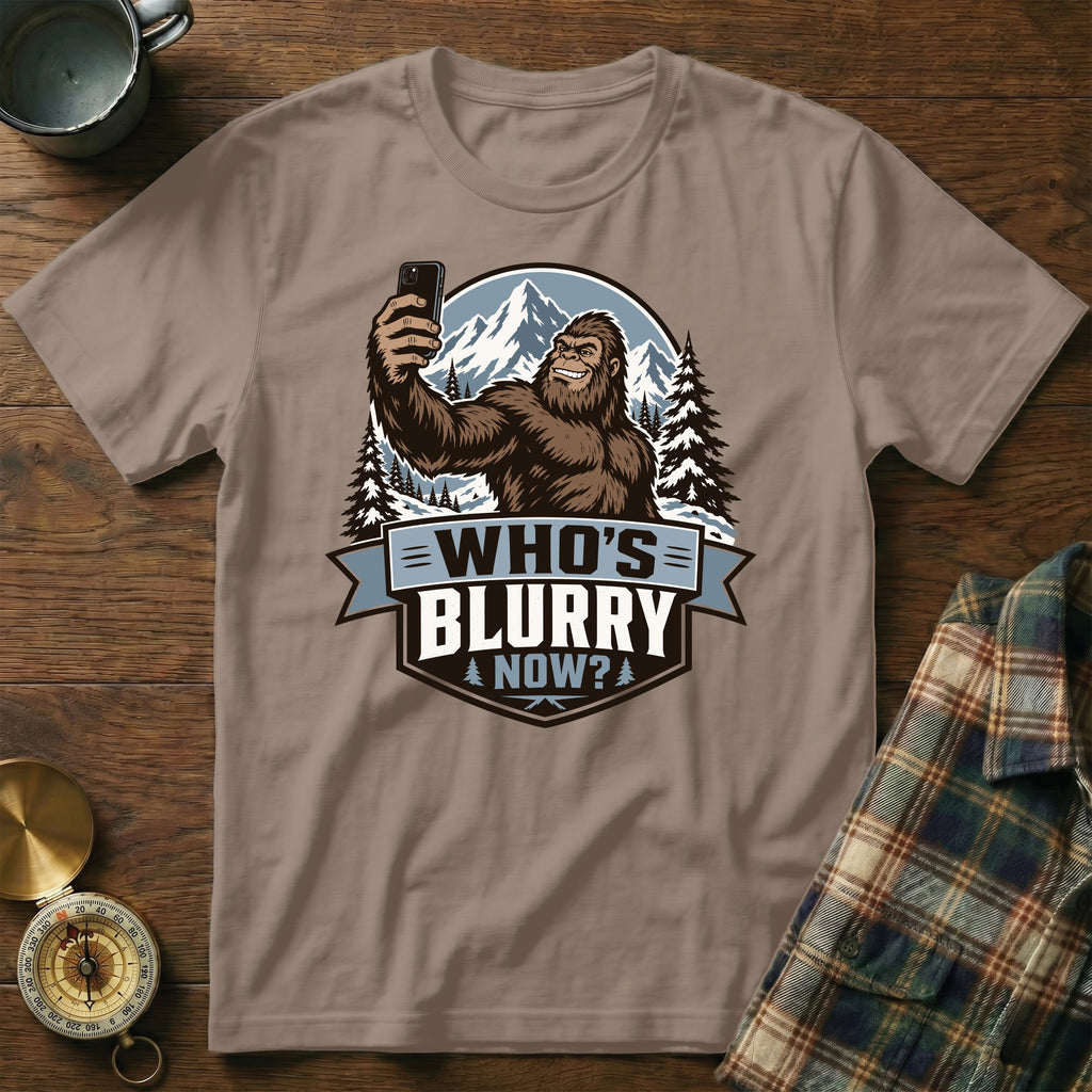 Bigfoot taking a selfie with mountains and trees, text "WHO'S BLURRY NOW?".