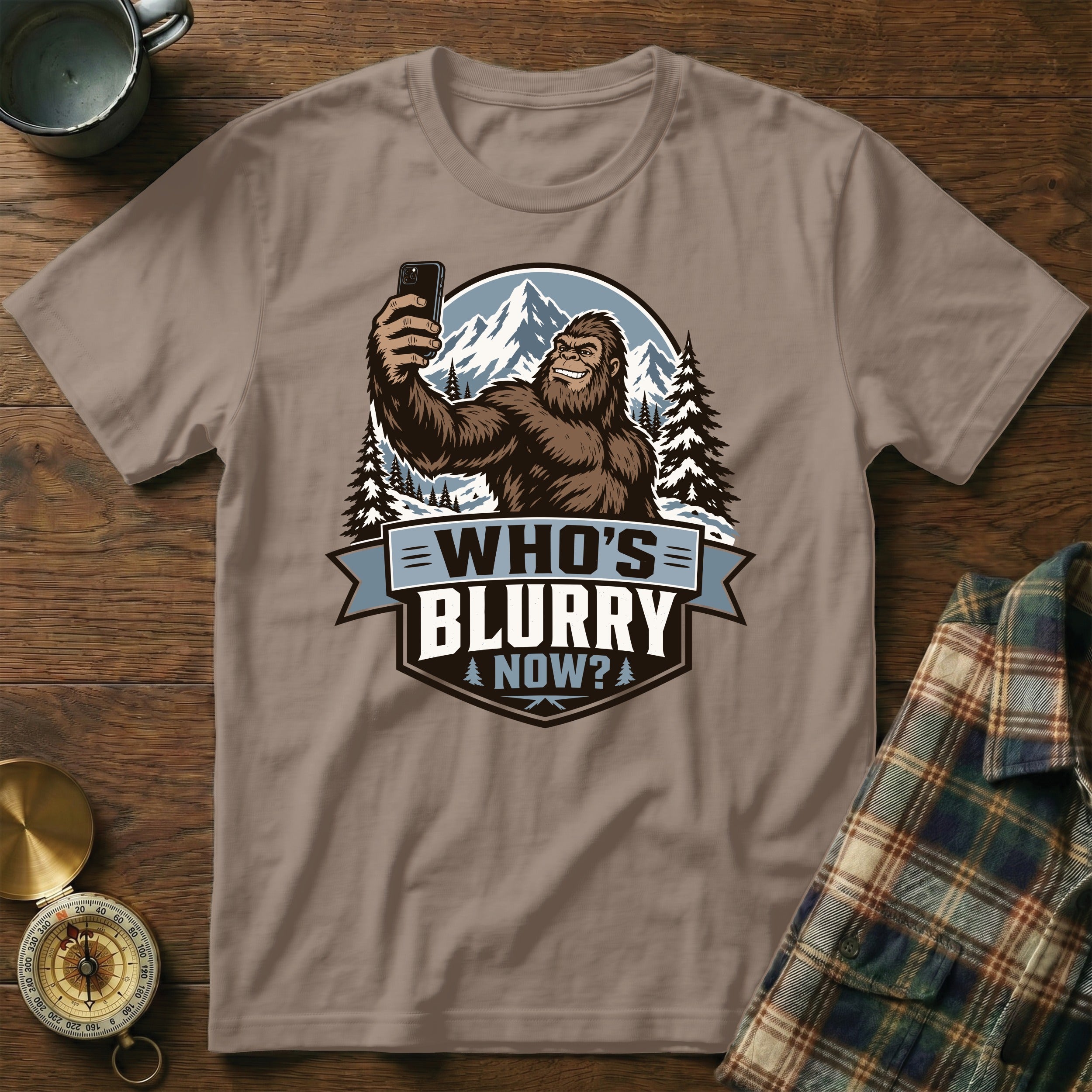 Bigfoot taking a selfie with mountains and trees, text "WHO'S BLURRY NOW?".