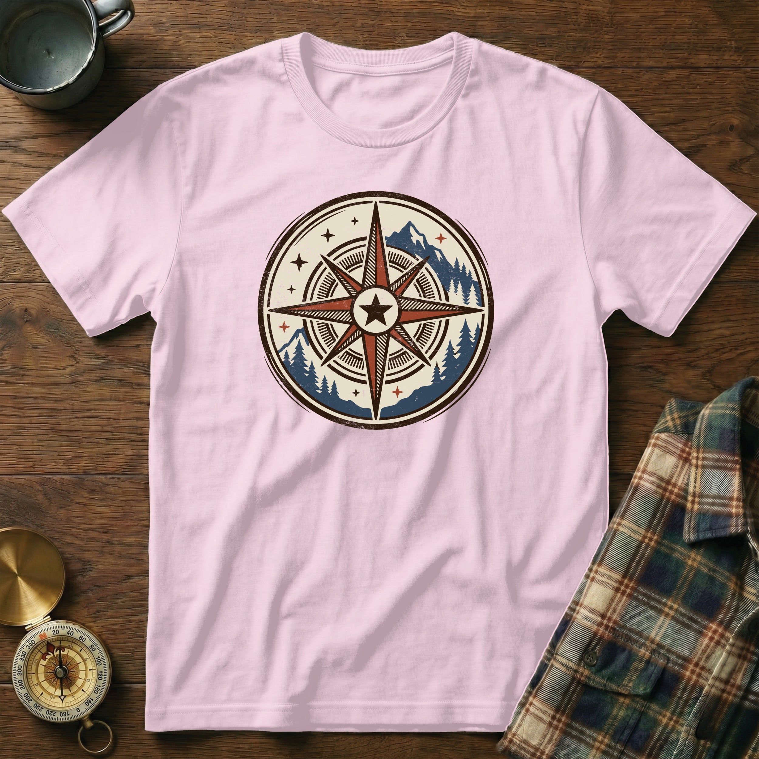 Pink t-shirt with a circular compass design featuring a mountain and tree landscape.