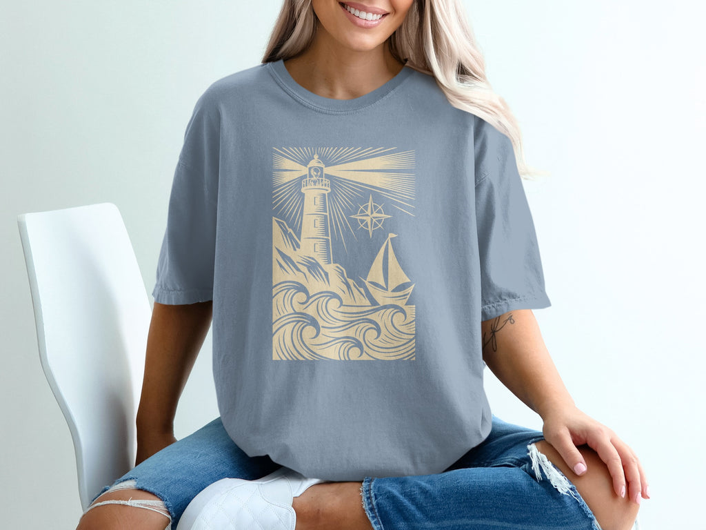 Light blue t-shirt with lighthouse, sailboat, and compass design.