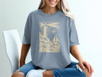 Light blue t-shirt with lighthouse, sailboat, and compass design.