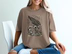 Brown t-shirt with graphic of an osprey diving for fish in choppy waves.