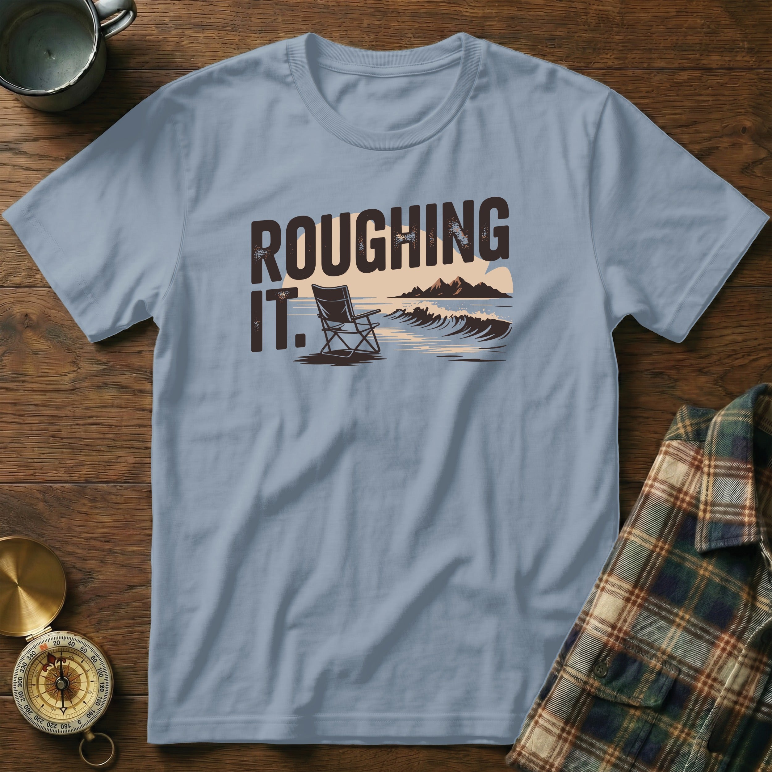 Light blue t-shirt with "ROUGHING IT." text and beach scene graphic.