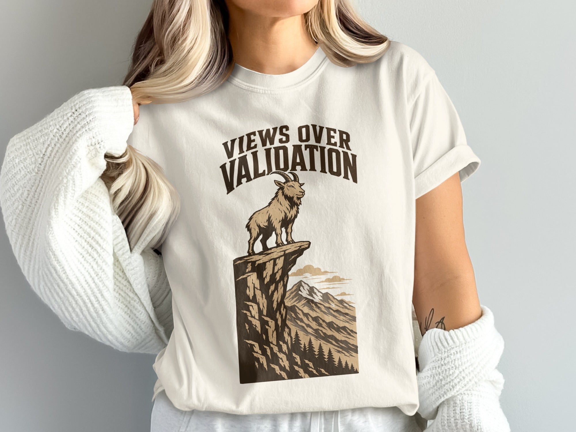 White t-shirt graphic with text "Views Over Validation" and a goat on a cliff.