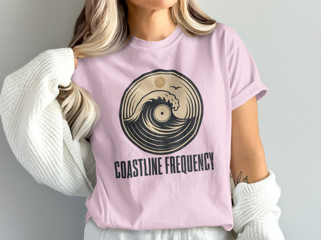 Pink t-shirt with circular wave and sun graphic and "COASTLINE FREQUENCY" text.