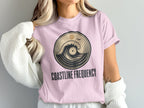 Pink t-shirt with circular wave and sun graphic and "COASTLINE FREQUENCY" text.