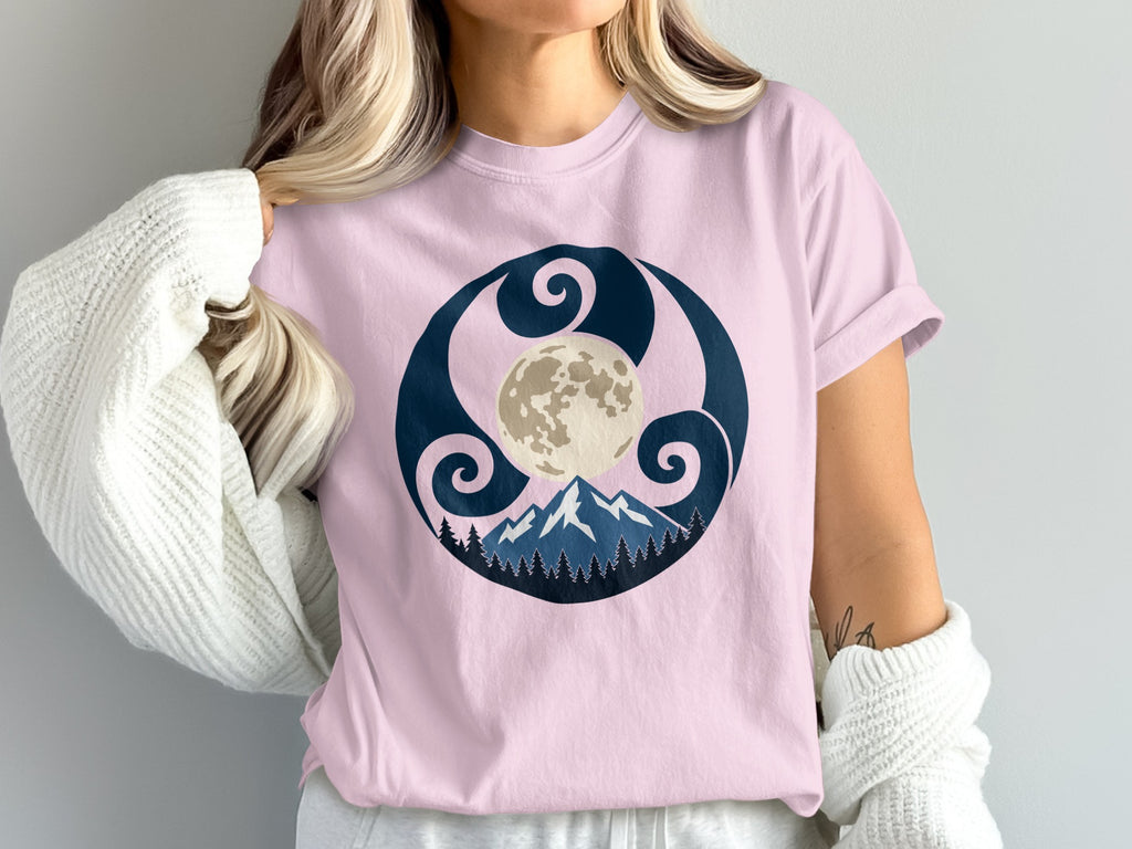 Pink t-shirt with a circular graphic of moon, mountains, and trees.