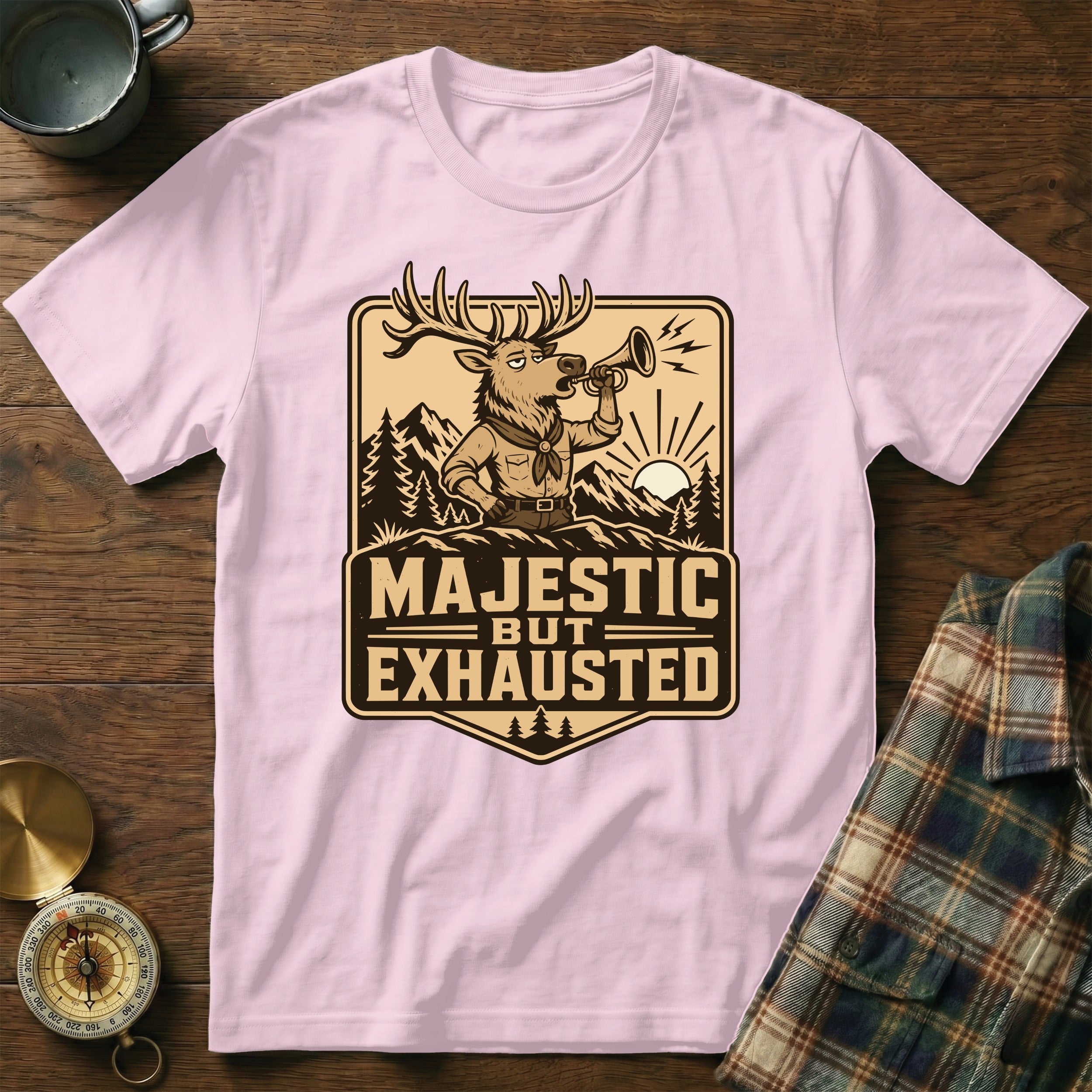 Pink t-shirt with "Majestic But Exhausted" text and a tired cartoon deer blowing a horn.