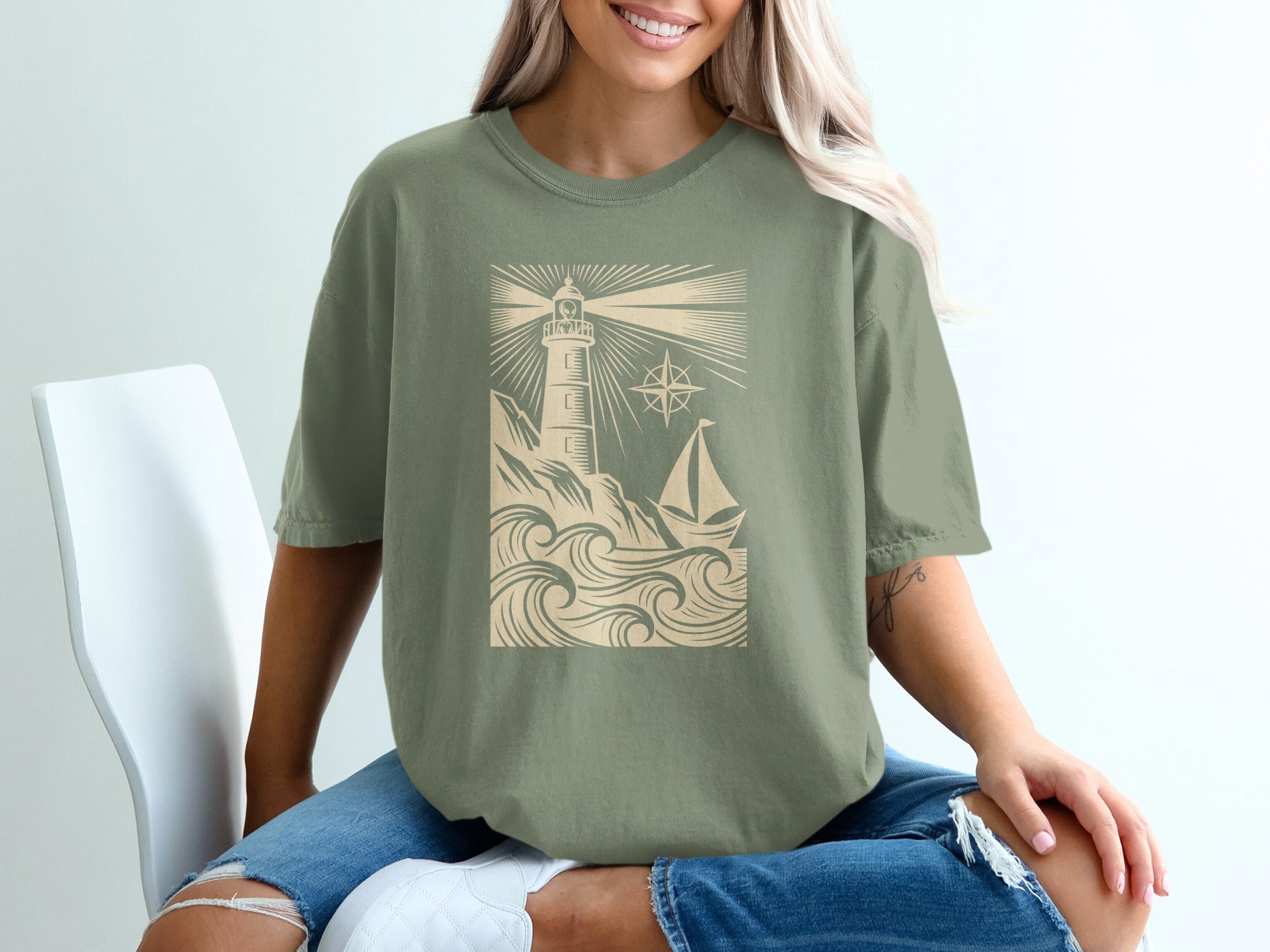 Lightbulb lighthouse and sailboat graphic on an olive green t-shirt.