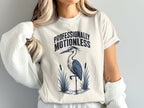 Cream t-shirt with "PROFESSIONALLY MOTIONLESS" and a heron graphic.
