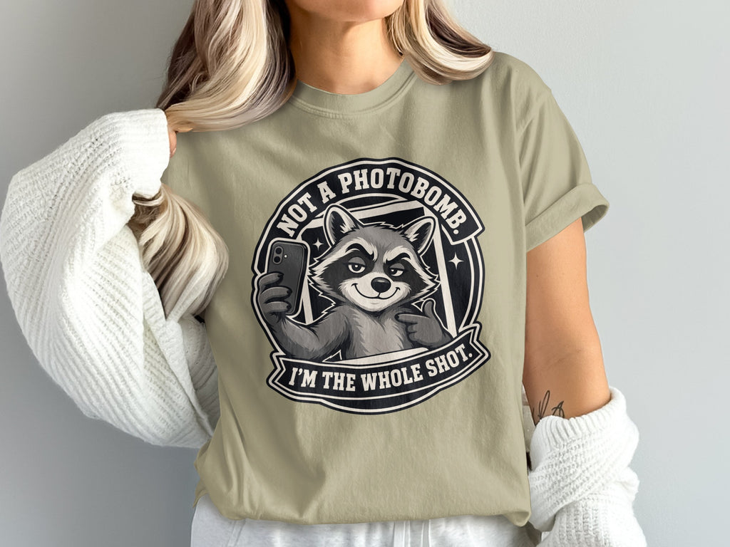 T-shirt graphic featuring a raccoon taking a selfie with text "NOT A PHOTOBOMB. I'M THE WHOLE SHOT."