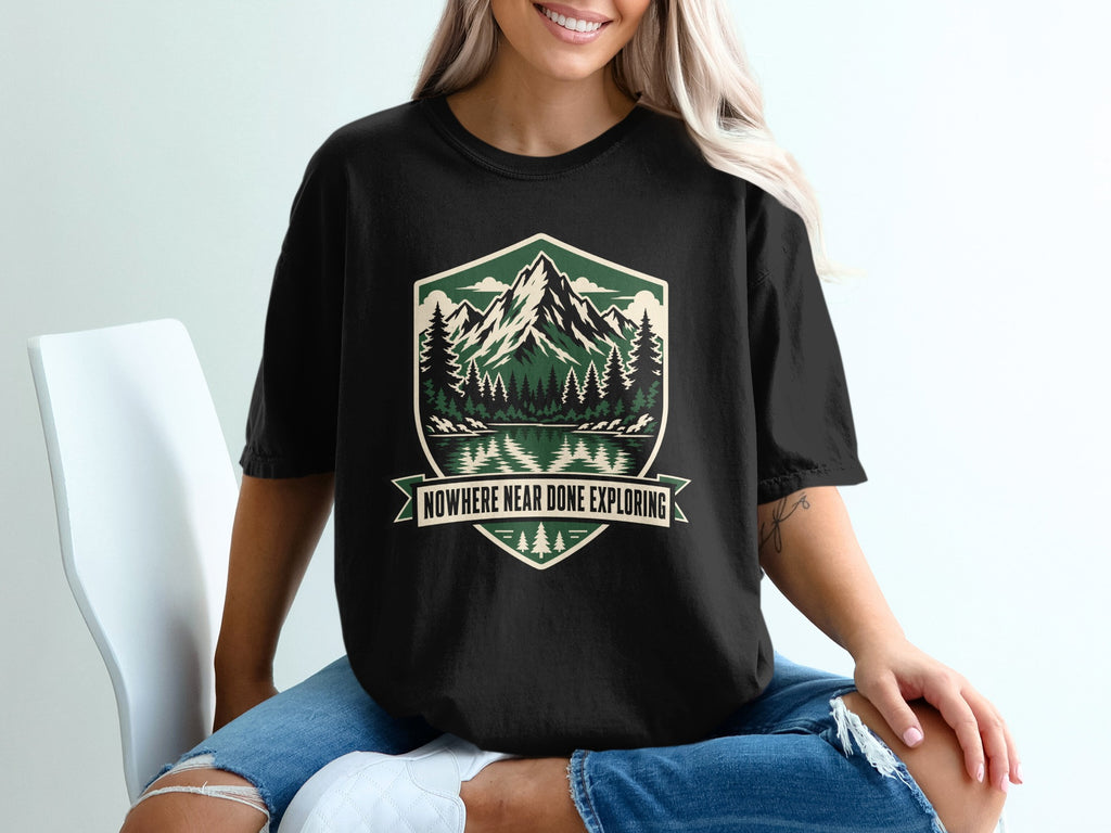 Black t-shirt with a nature scene graphic and text "NOWHERE NEAR DONE EXPLORING".