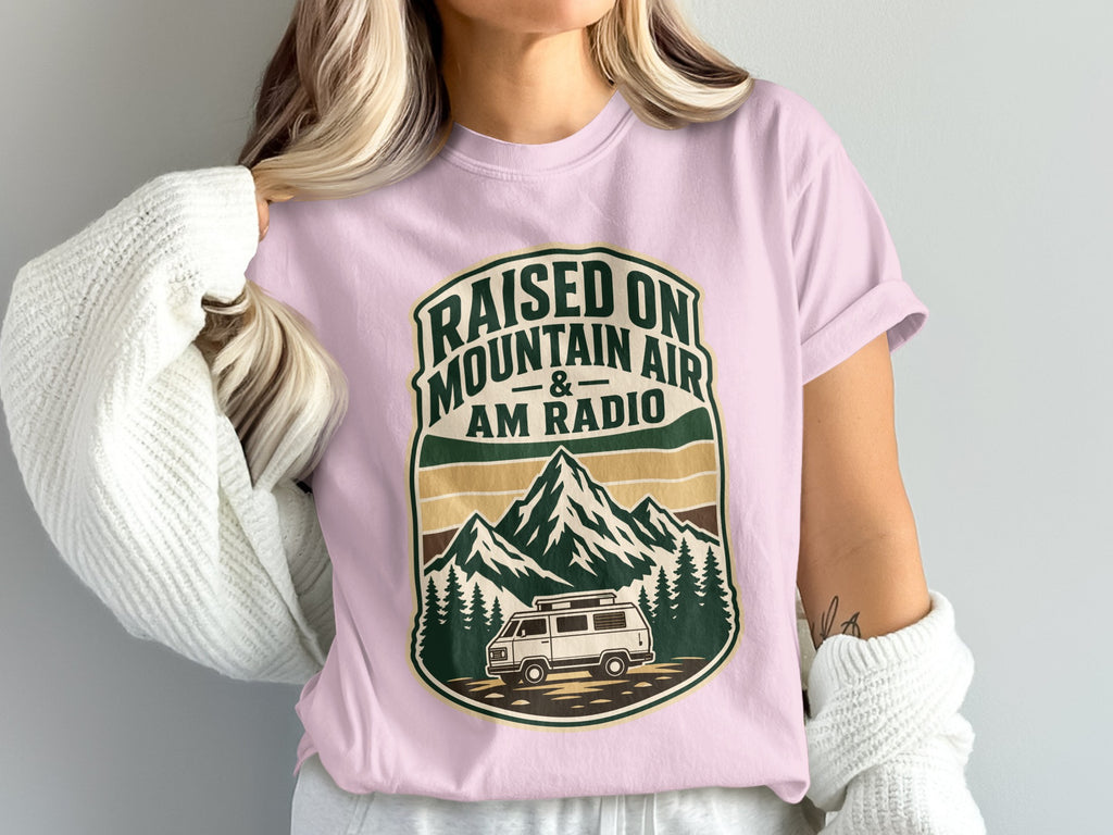 Pink t-shirt with "Raised on Mountain Air & AM Radio" graphic featuring mountains and van.