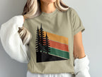 T-shirt with stylized pine trees and retro striped sunset graphic.
