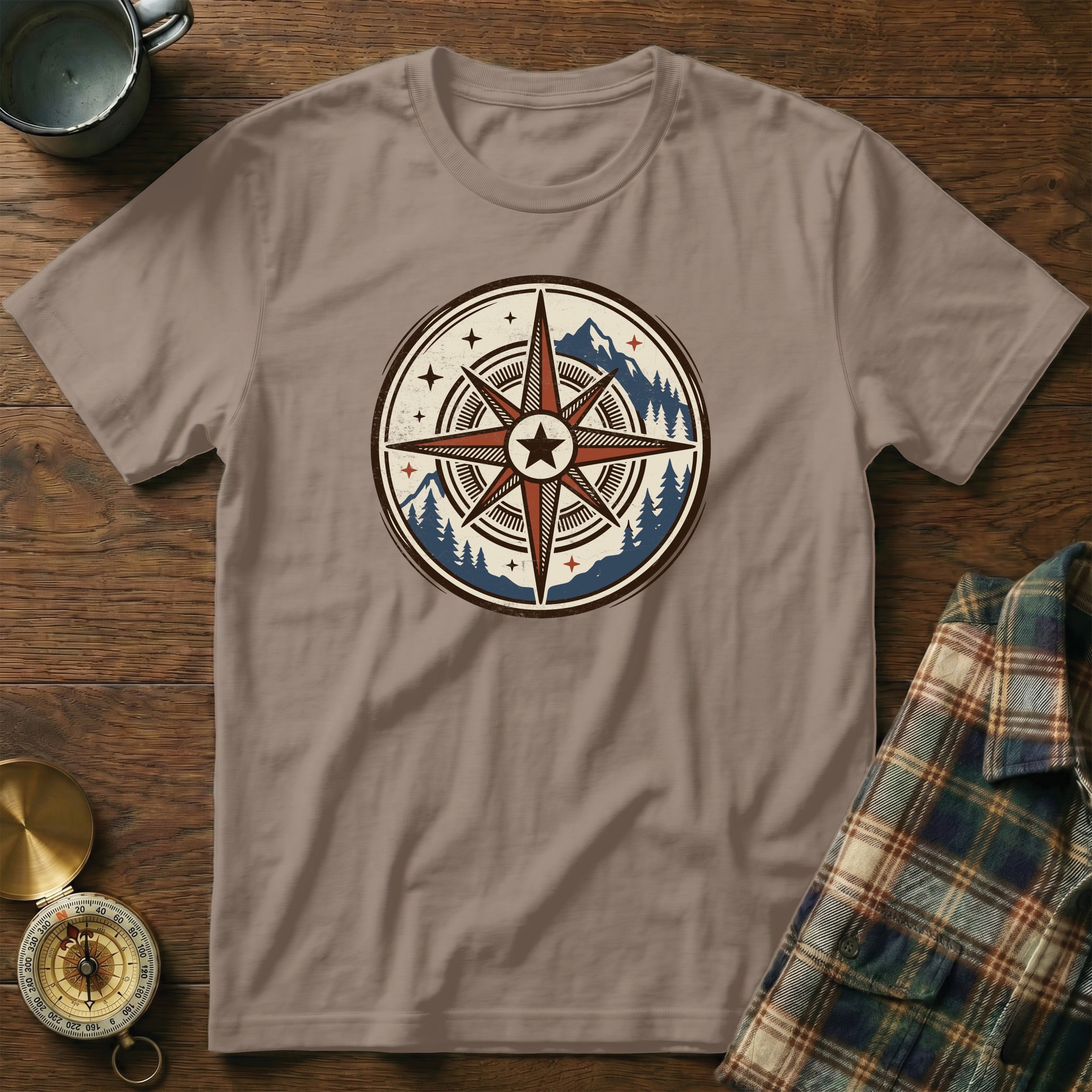 Light brown t-shirt with a circular compass design featuring mountains and trees.