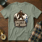 Graphic tee with a walking Bigfoot wearing sunglasses and the text "Spotted Not Sorry".