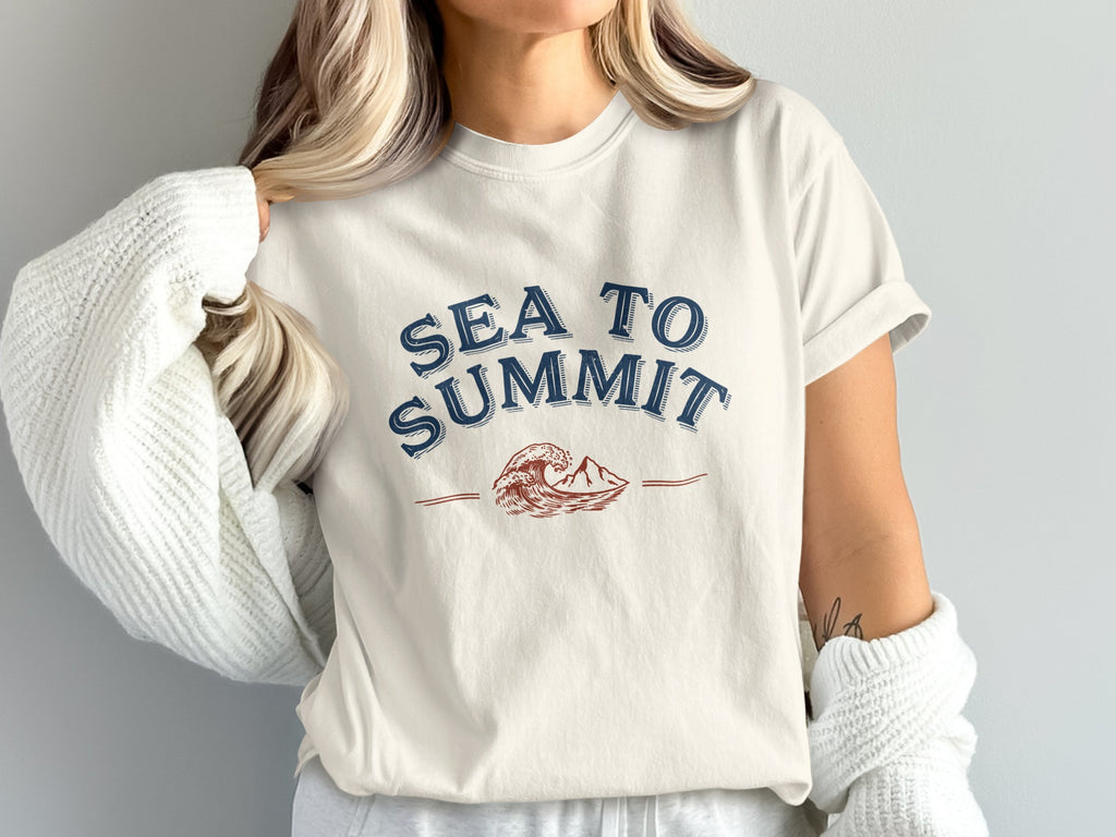 Cream t-shirt with blue "SEA TO SUMMIT" text and wave and mountain graphic.
