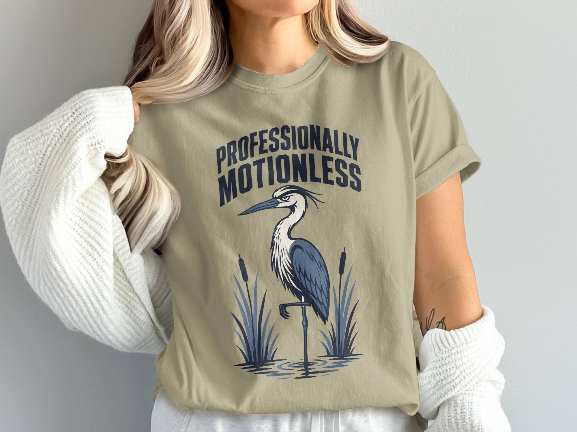 T-shirt with "PROFESSIONALLY MOTIONLESS" text and a blue heron in reeds.