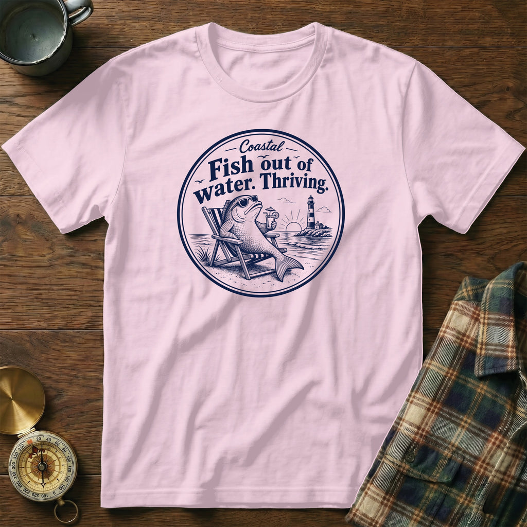 A light pink crewneck t-shirt featuring a circular blue graphic of a fish lounging in a beach chair with a drink.
