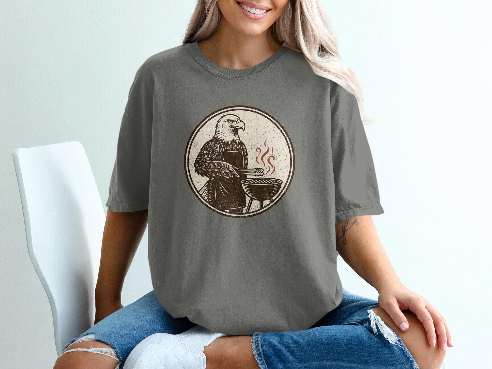 Eagle wearing an apron, grilling at a barbecue, line art graphic on a t-shirt.