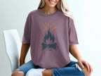 Purple t-shirt with a dark gray campfire graphic and orange sparks.