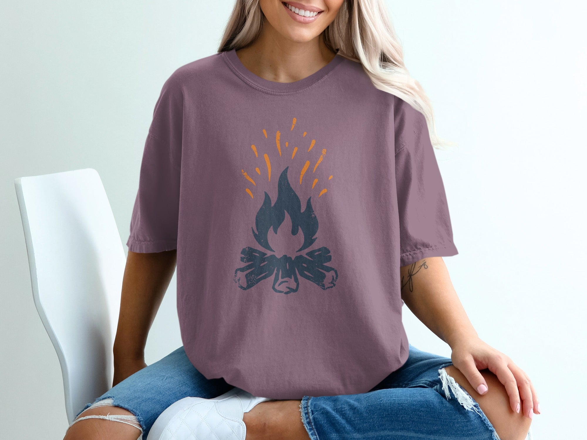Purple t-shirt with a dark gray campfire graphic and orange sparks.