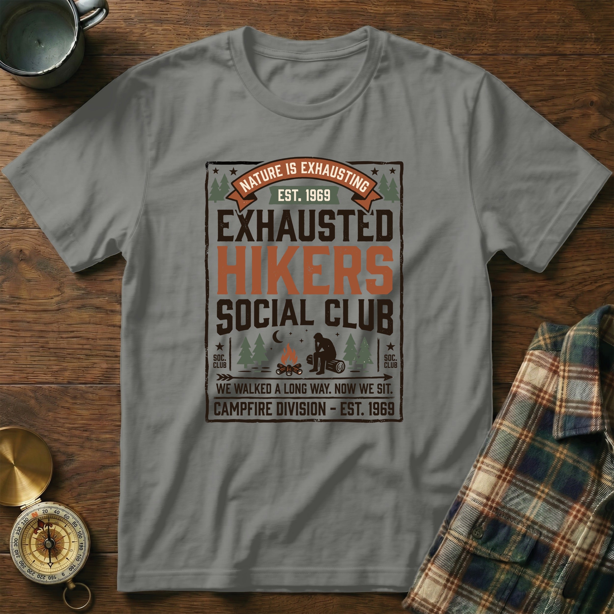 "Exhausted Hikers Social Club" t-shirt with campfire and nature graphics.