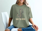 Olive green t-shirt with anchor and rope graphic and "SALT & IRON" text.
