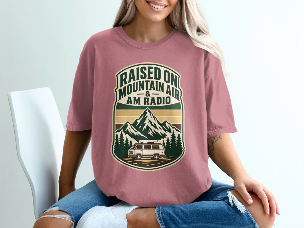 T-shirt graphic with text "Raised on mountain air & AM radio" and a van.
