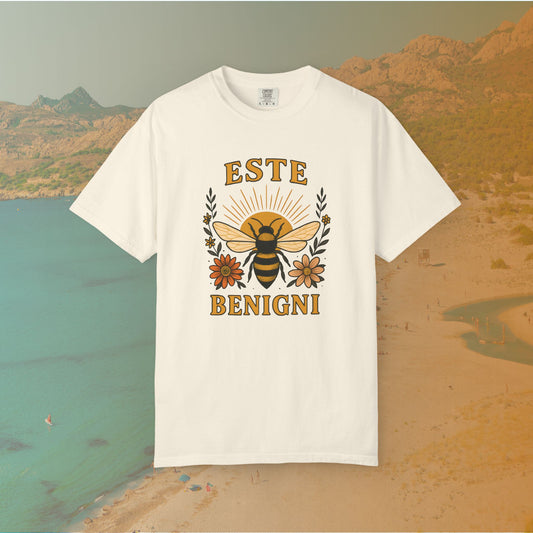 ivory t-shirt Vintage-style graphic tee featuring a large, central honey bee with sunburst wings, flanked by retro flowers. The Latin words "ESTE BENIGNI" for "BEE KIND" are printed above and below the design.