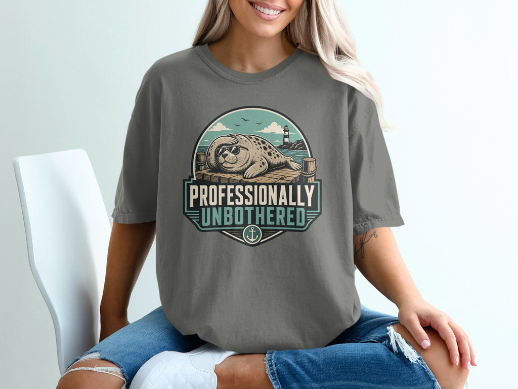 T-shirt graphic with seal on dock, lighthouse, and text "Professionally Unbothered."