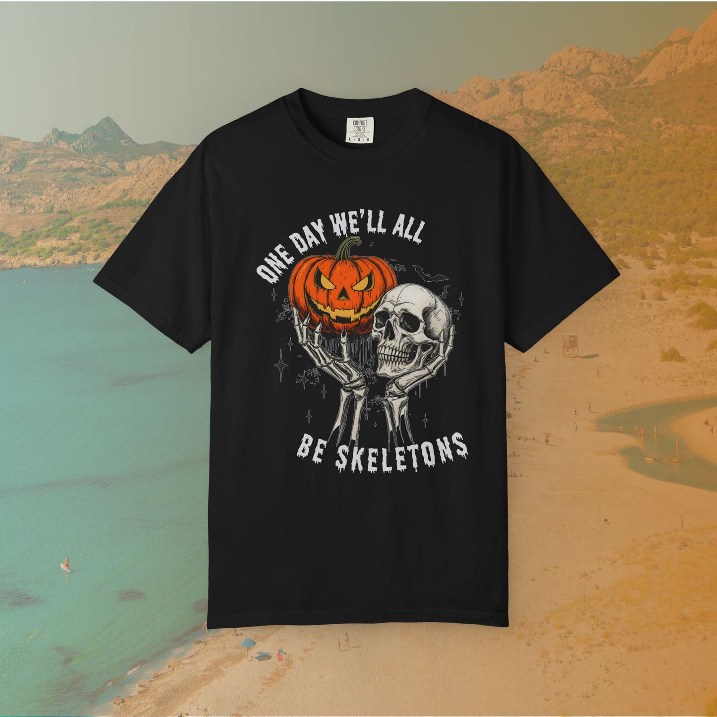 Skeleton hands holding a jack-o'-lantern and skull with the phrase ‘One Day We’ll All Be Skeletons’ in grunge font