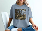 Bigfoot stands on a cliff overlooking a rough ocean with trees.
