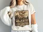 T-shirt graphic: deer blowing horn in mountains, text "Majestic But Exhausted."