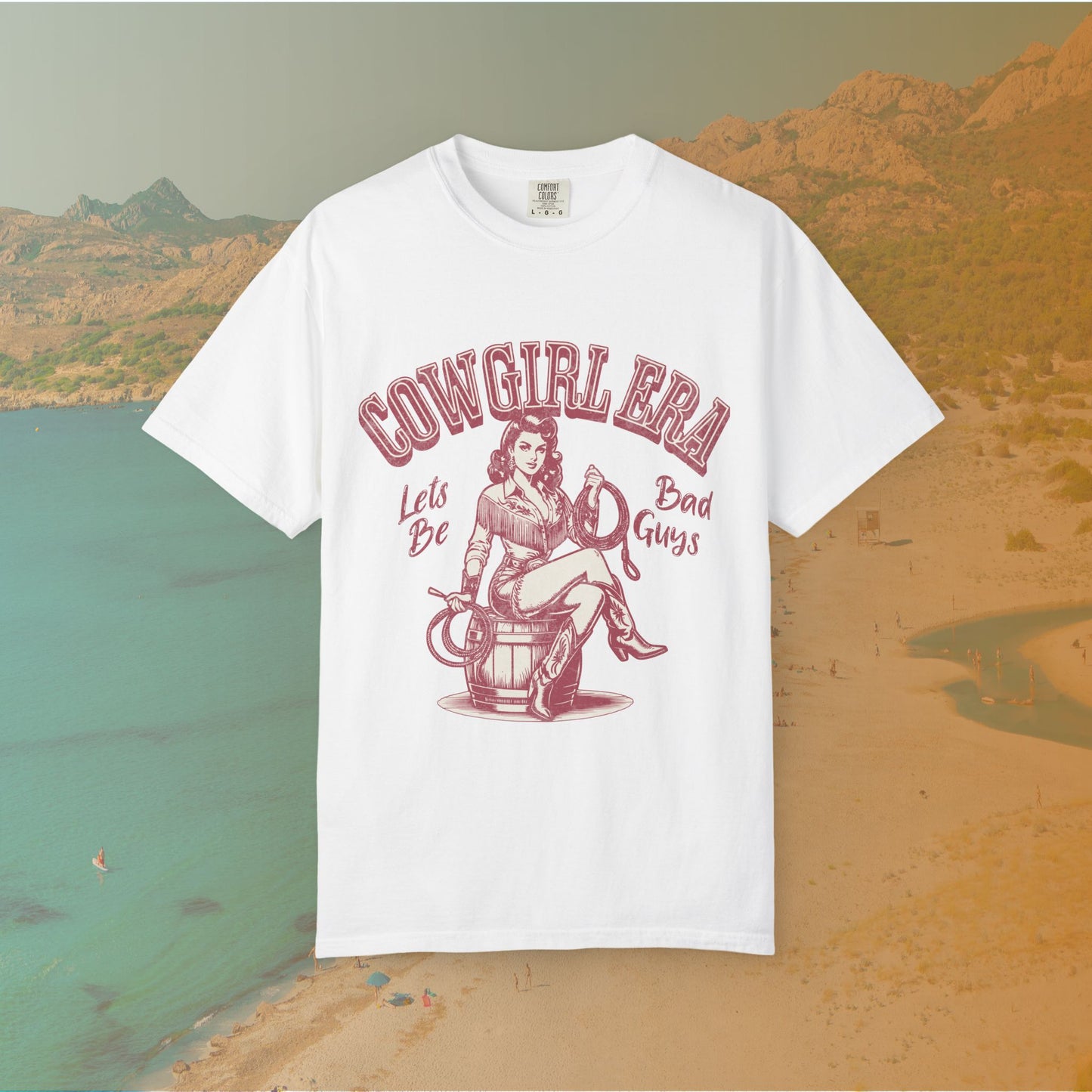 Cowgirl Era pinup T-shirt with a vintage-style illustration of a sassy cowgirl sitting on a barrel holding a lasso. The graphic includes the text "COWGIRL ERA" and "Lets Be Bad Guys.