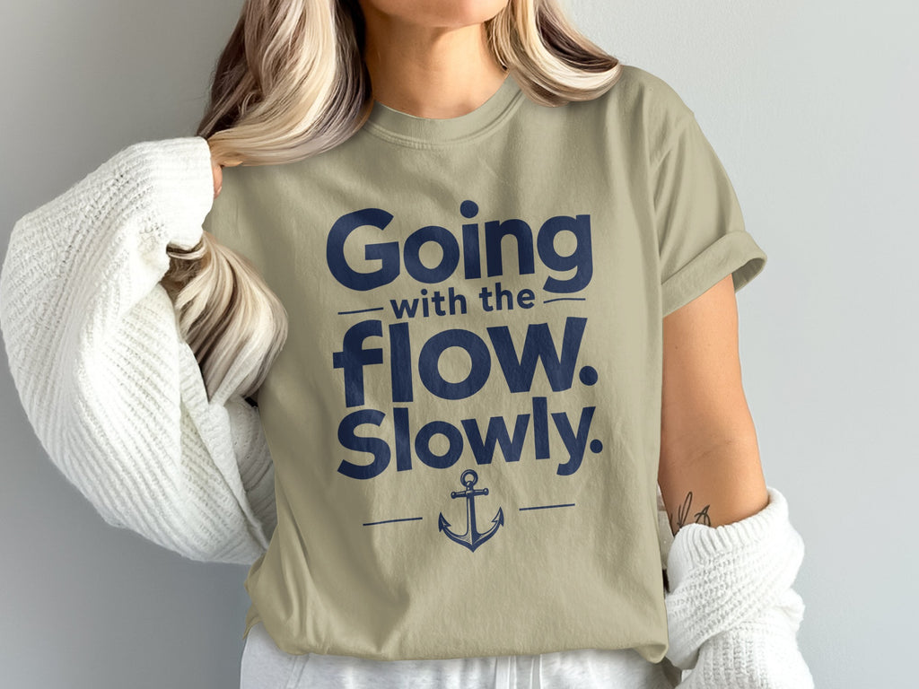 A woman wearing an olive-green t-shirt printed with dark blue text reading Going with the flow. Slowly. and an anchor graphic.