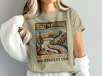 Desert to Mountains Adventure graphic t-shirt with mountains, cacti, and sunset.