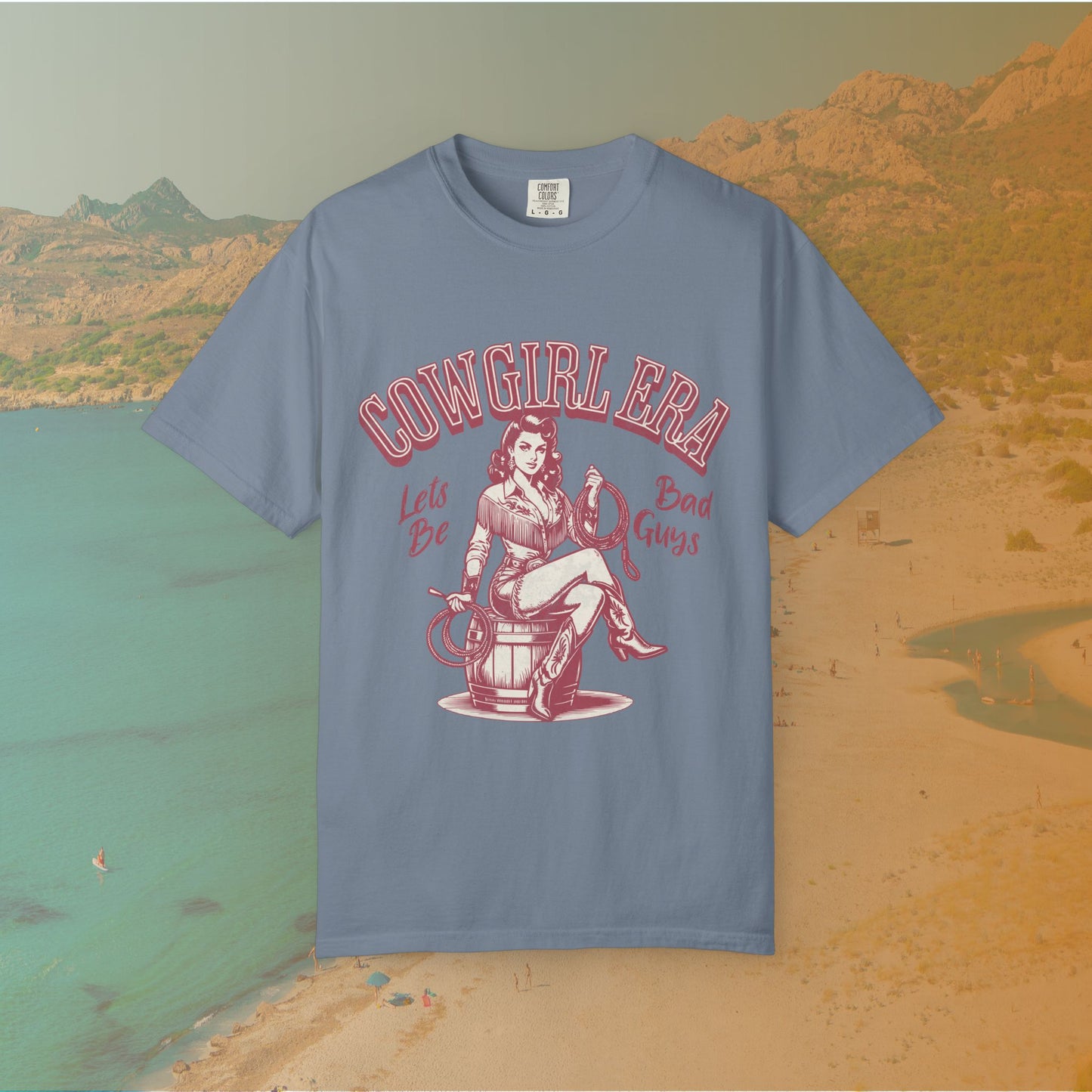 Cowgirl Era pinup T-shirt with a vintage-style illustration of a sassy cowgirl sitting on a barrel holding a lasso. The graphic includes the text "COWGIRL ERA" and "Lets Be Bad Guys.
