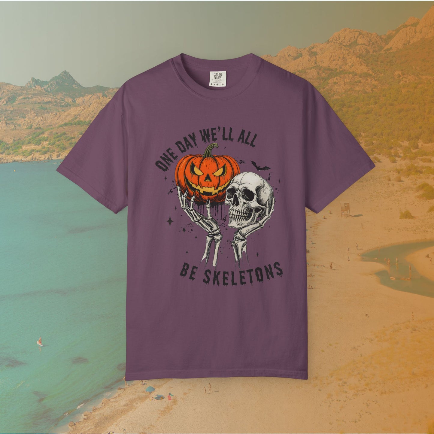 Skeleton hands holding a jack-o'-lantern and skull with the phrase ‘One Day We’ll All Be Skeletons’ in grunge font