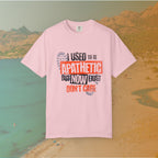 pink Graphic T-shirt featuring the layered, distressed text: "I USED TO BE APATHETIC BUT NOW I JUST DON'T CARE," overlaid with halftone dot textures and boot print graphics.