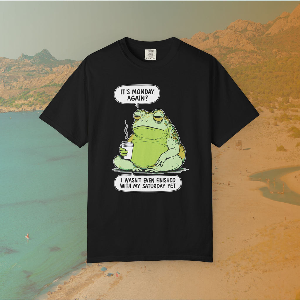 Black T-shirt Funny T-shirt graphic featuring a large, grumpy toad holding a to-go coffee cup. The cartoon is captioned with the quotes: "IT'S MONDAY AGAIN? I WASN'T EVEN FINISHED WITH MY SATURDAY YET.
