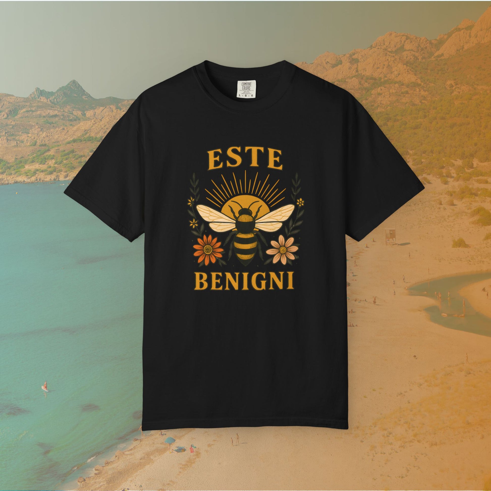 black t-shirt Vintage-style graphic tee featuring a large, central honey bee with sunburst wings, flanked by retro flowers. The Latin words "ESTE BENIGNI" for "BEE KIND" are printed above and below the design.
