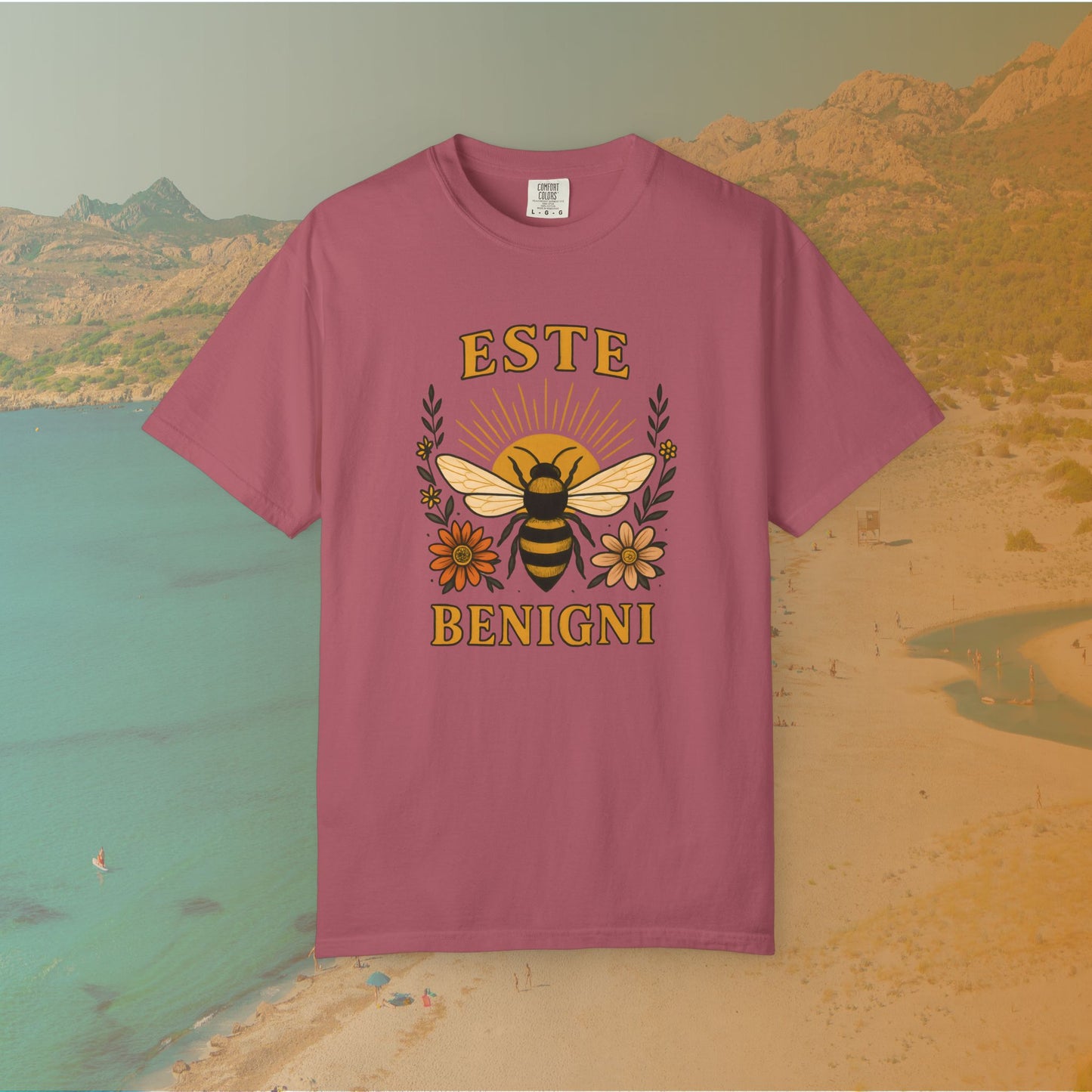 pink t-shirt Vintage-style graphic tee featuring a large, central honey bee with sunburst wings, flanked by retro flowers. The Latin words "ESTE BENIGNI" for "BEE KIND" are printed above and below the design.