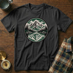 Black t-shirt with a circular mountain and lake graphic, compass, and folded plaid shirt.