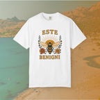 white t-shirt Vintage-style graphic tee featuring a large, central honey bee with sunburst wings, flanked by retro flowers. The Latin words "ESTE BENIGNI" for "BEE KIND" are printed above and below the design.