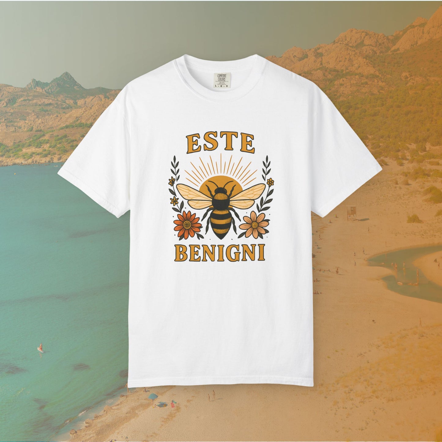 white t-shirt Vintage-style graphic tee featuring a large, central honey bee with sunburst wings, flanked by retro flowers. The Latin words "ESTE BENIGNI" for "BEE KIND" are printed above and below the design.