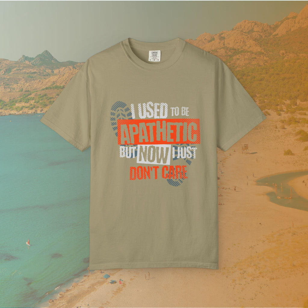 khaki Graphic T-shirt featuring the layered, distressed text: "I USED TO BE APATHETIC BUT NOW I JUST DON'T CARE," overlaid with halftone dot textures and boot print graphics.