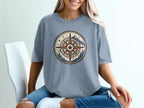 Blue t-shirt with a circular compass design featuring mountains and trees.