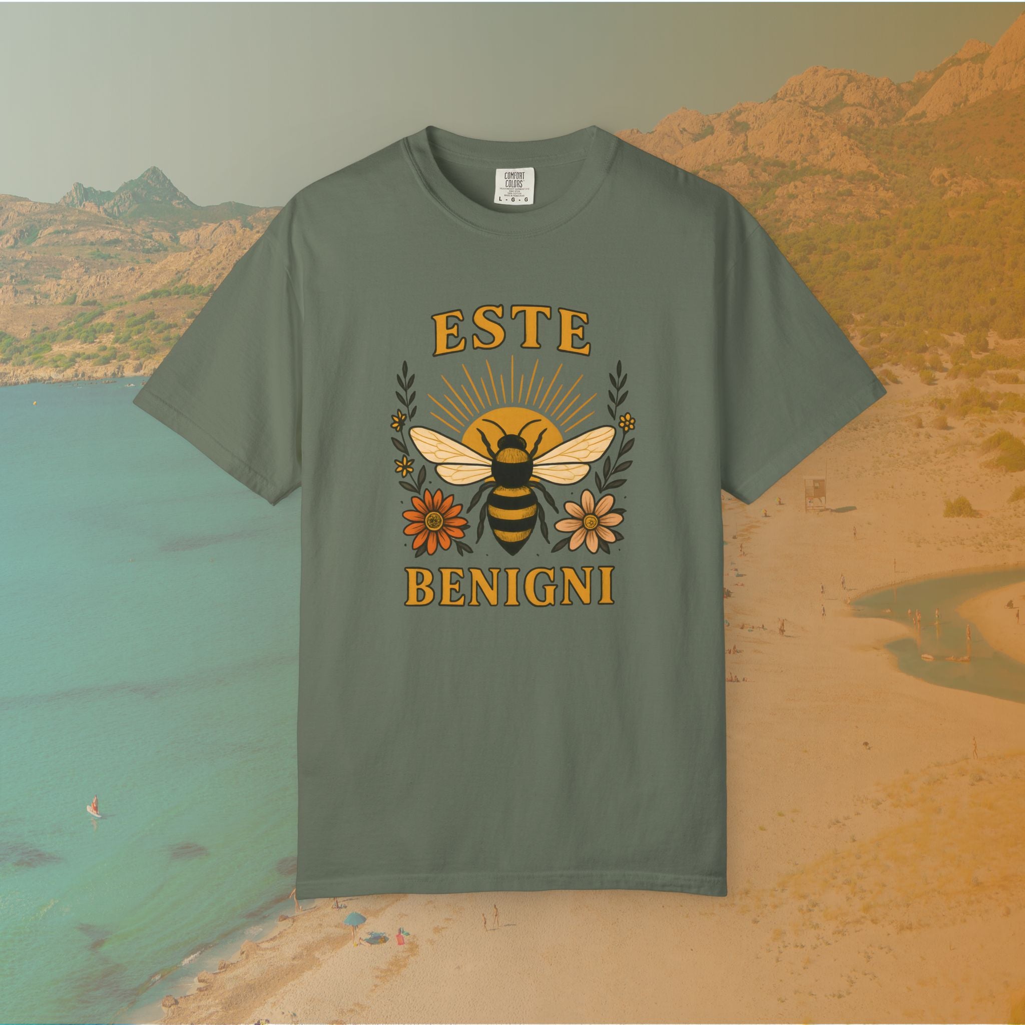green t-shirt Vintage-style graphic tee featuring a large, central honey bee with sunburst wings, flanked by retro flowers. The Latin words "ESTE BENIGNI" for "BEE KIND" are printed above and below the design.
